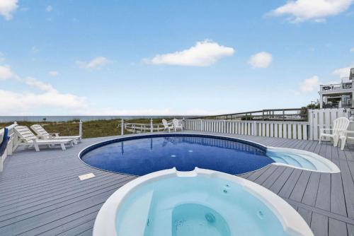 a swimming pool on a deck with chairs and a deck at SEA2SKY Ocean front private pool and spa in Kure Beach