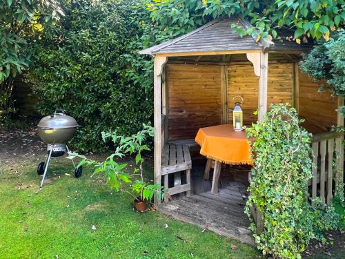 a table and a grill next to a wooden shed at Rosehill in Truro
