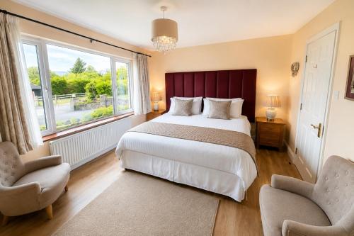 ein Schlafzimmer mit einem großen Bett und zwei Stühlen in der Unterkunft Edencrest B&B in Bantry