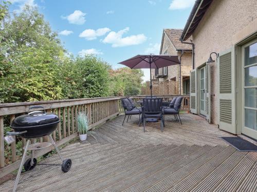 a grill on a deck with a table and chairs at Riverview in Somerford Keynes