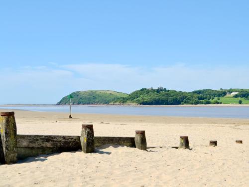 a beach with a wooden fence in the sand at Ysgubor Wen in Burry Port