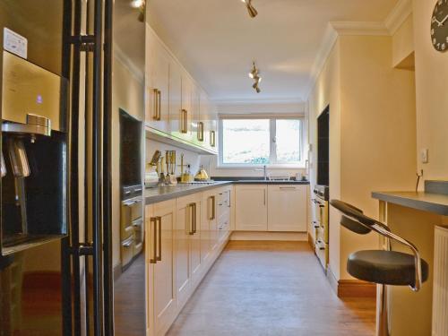 a kitchen with white cabinets and a black refrigerator at Ysgubor Wen in Burry Port