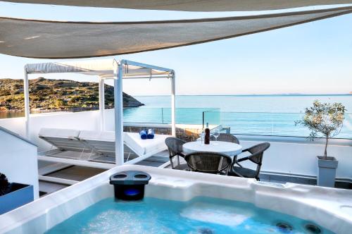 a bath tub with a table and chairs and the ocean at Seafront Villa Moments, by Estia in Mochlos