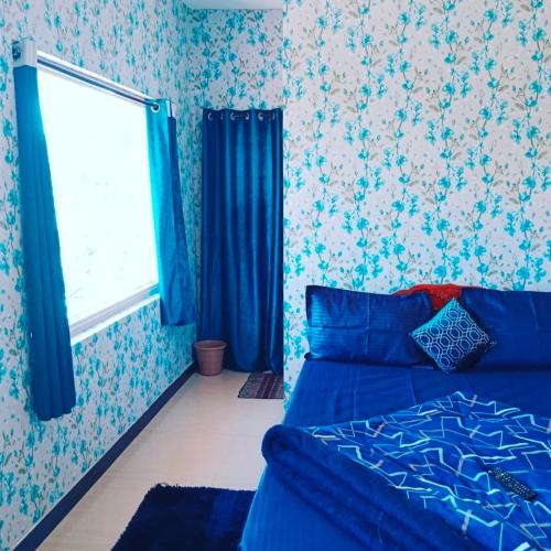 a bedroom with a blue bed and a window at Blue Pearl Cottage in Ooty