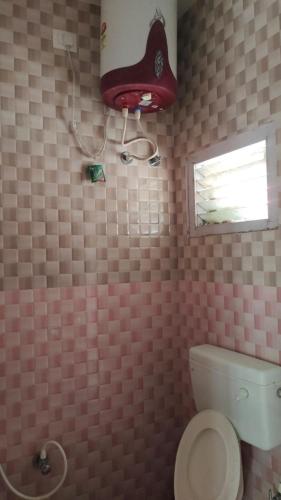 a bathroom with a toilet and a red hat on the wall at Blue Pearl Cottage in Ooty
