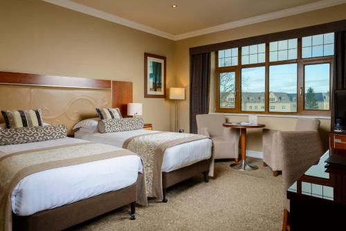 a hotel room with two beds and a chair at The Brehon Hotel & Spa in Killarney