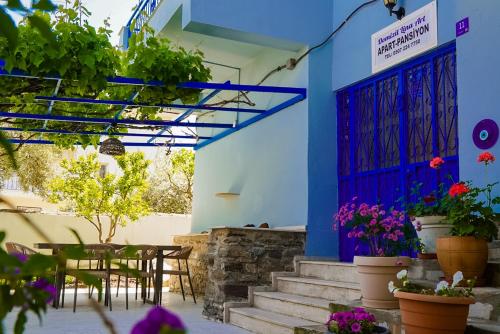 a patio with a blue door and tables and potted plants at Domizil Lina Art in Güzelçamlı