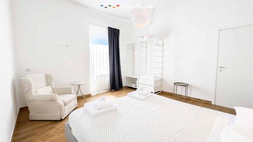 a white bedroom with a bed and a chair at Il Posto Perfetto, Terre Marine in Corvara