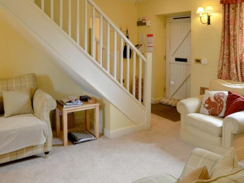 a living room with two chairs and a staircase at The Old Stables in Uldale