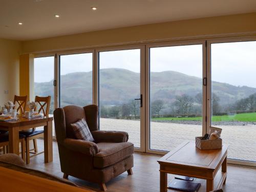 a living room with a chair and a table and windows at Sweet Meadow Lodge in Llandrindod Wells