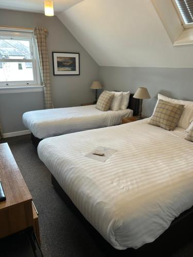 a bedroom with two beds and a window at Loch Ness Guest House in Fort Augustus