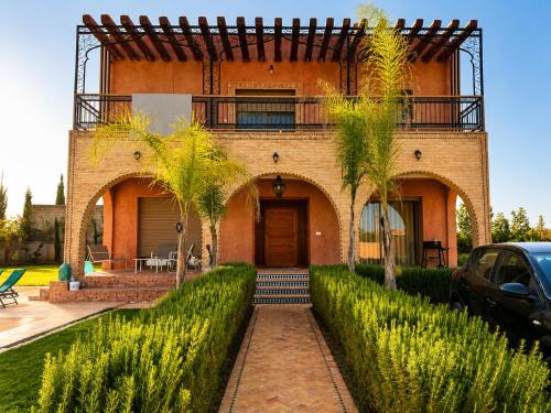 a brick house with a balcony on top of it at VILLA Les 3 Palmiers in Amezrou
