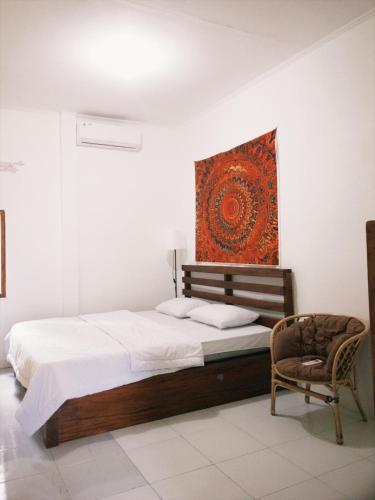 a bedroom with a bed and a chair and a painting at beaches Lyfe Rooms in Kuta Lombok