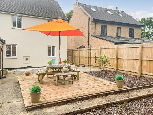 a wooden deck with a picnic table and an umbrella at Mills Croft in Hognaston