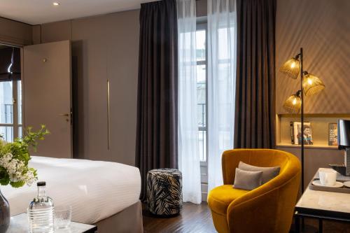 a hotel room with a bed and a yellow chair at Hotel Le 10 BIS in Paris