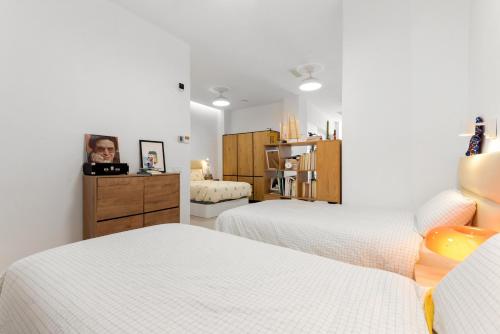 a white bedroom with two beds and a dresser at La casa del Pan in Málaga
