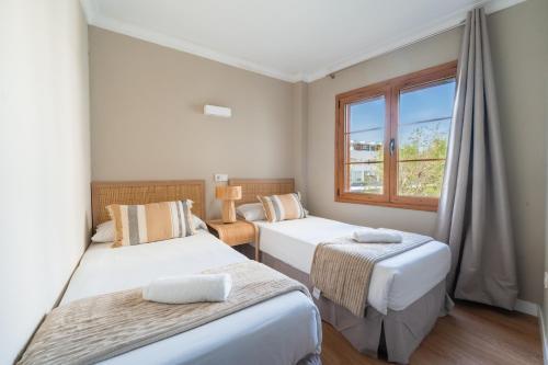 two beds in a room with a window at CARABELA 92 in Alcudia