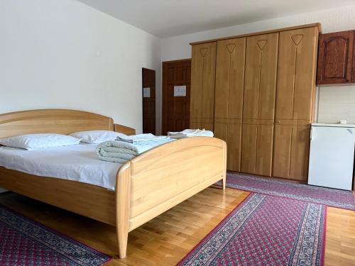 a bedroom with a wooden bed and a refrigerator at Apartments Vicko in Brzeće