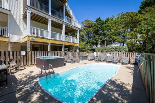a swimming pool in front of a house with chairs at Oceanside retreat with pool & spa June Weeks Open in Sanderling