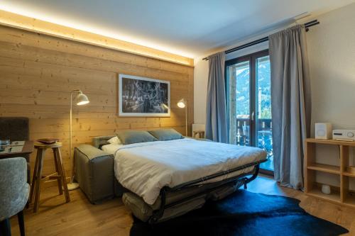a bedroom with a bed and a large window at Balmoral in Champéry