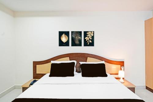 a bedroom with a white bed with a wooden headboard at Hotel O Anantapur in Anantapur
