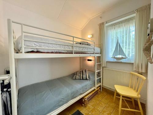 a bedroom with two bunk beds and a chair at Holiday home Zeeroos in Koudekerke
