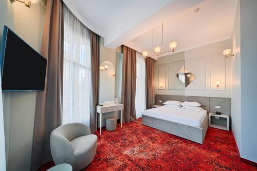 a bedroom with a bed and a tv and a chair at Hotel Central in Ploieşti