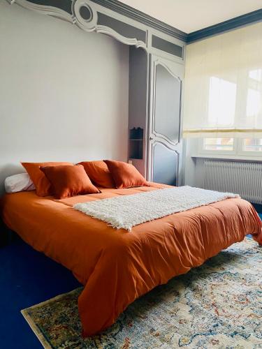 a bed with an orange comforter in a room at L'escale vosgienne in Saint Die