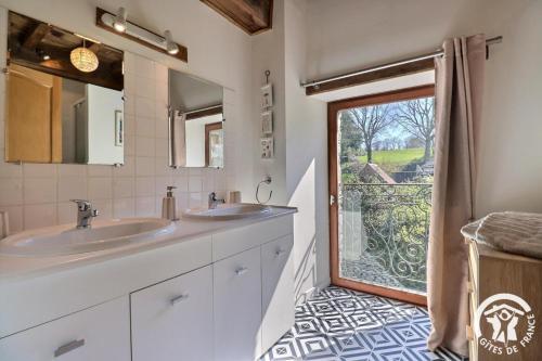 a bathroom with two sinks and a sliding glass door at Le gué de brocéliande in Plélan-le-Grand