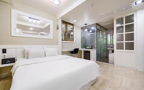 a white bedroom with a large bed and a bathroom at 자자호텔 in Goseong
