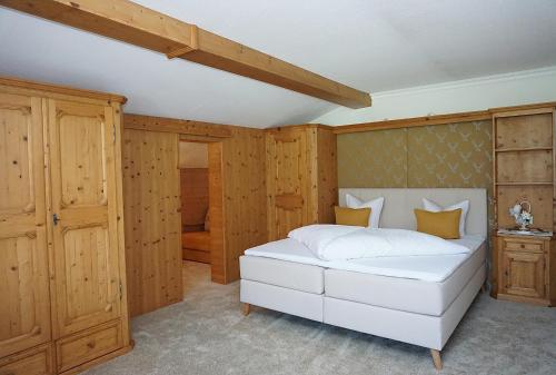 a bedroom with a white bed and wooden walls at Landhaus Achental in Pertisau