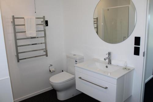 a white bathroom with a toilet and a mirror at Stargate Retreat - Lake Tekapo in Lake Tekapo