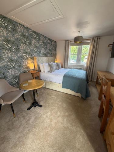 a bedroom with a bed and a table and a window at Little Fairfield in Ashover