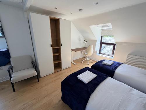 two beds in a room with a desk and a chair at The Rock House in Cobh