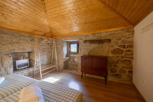 a bedroom with a bed and a fireplace in a stone wall at Casa Ti Nogueira in Soajo
