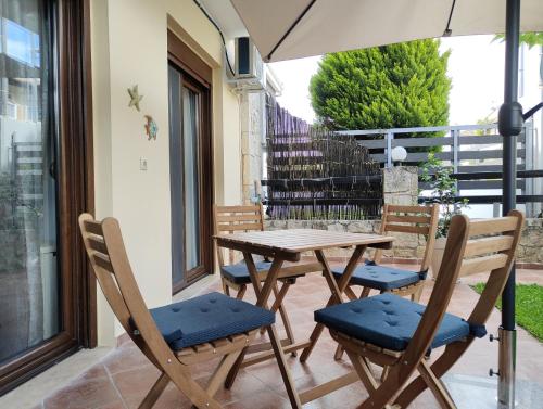 a wooden table and chairs with an umbrella on a patio at SiviriLovelyApartment in Siviri