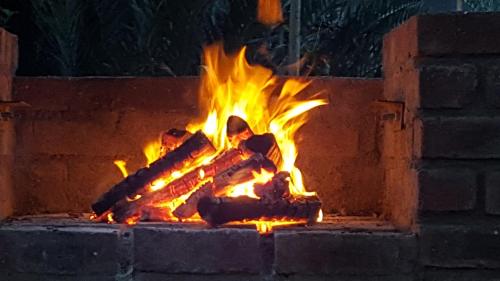 a fire in a brick fireplace at night at Kiaat Bungalows in Hazyview