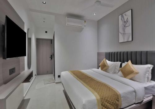 a bedroom with a large bed and a flat screen tv at Hotel Sunshine Suites IGI Airport in New Delhi