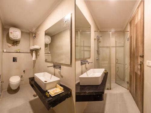 a bathroom with a sink and a toilet and a mirror at Hotel Sunshine Suites IGI Airport in New Delhi