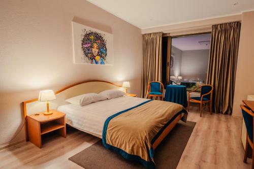 a hotel room with a bed and a table and chairs at Hotel Trotuş in Onești