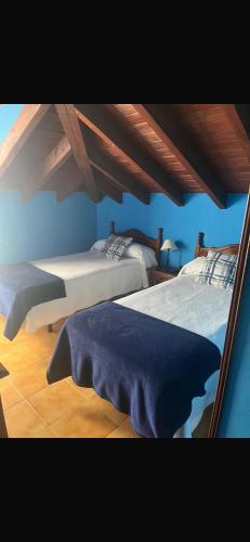 two beds in a room with blue walls at hosteria de Boo in Boó de Piélagos