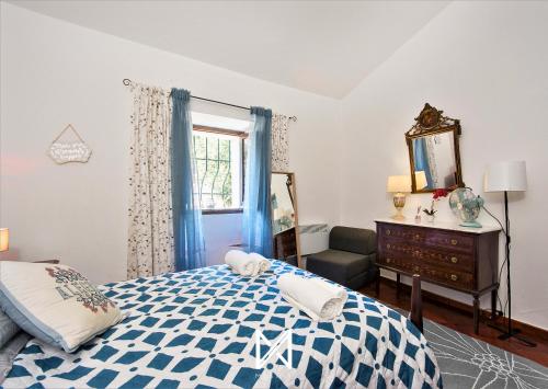 a bedroom with a blue and white bed and a mirror at MyStay - Monte dos Abrunhos in Vimieiro