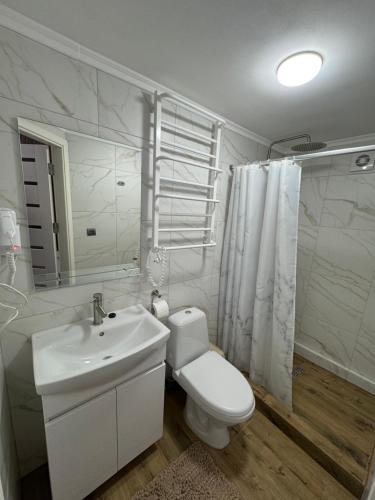 a white bathroom with a toilet and a sink at Vista Guest House in Yaremche