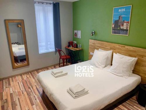 a large bed in a room with a green wall at Logis Hotel Yseria - Historical Center in Agde
