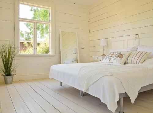 a white bedroom with a bed and a window at Mysiga Villan in Borgholm