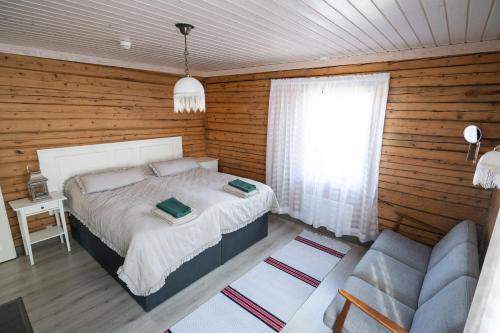 a bedroom with a bed and a couch and a window at Poromoision pirtti in Peurasuvanto