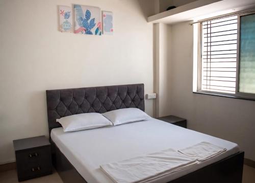 a bedroom with a large bed with white sheets and a window at Swami Homestay in Solapur