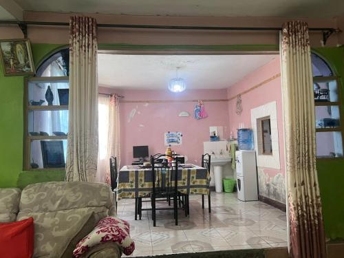 a living room with a table and a kitchen at PODLYNS Home in Ngong
