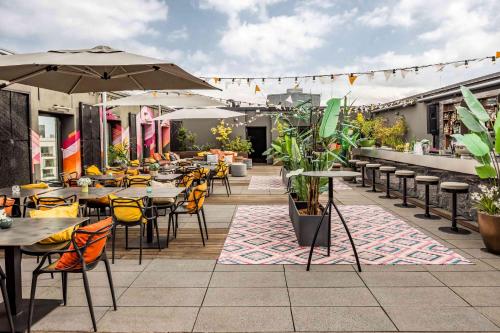 an outdoor patio with tables and chairs and plants at Hotel AMANO Grand Central in Berlin