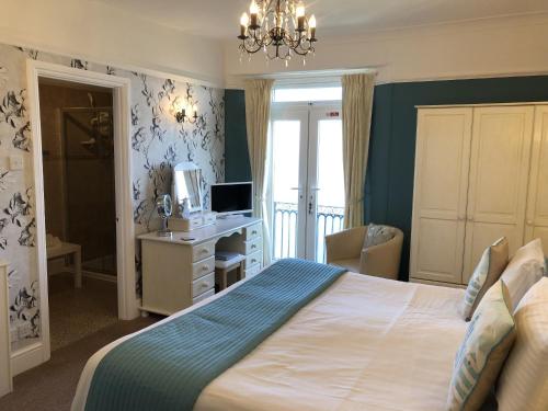 a bedroom with a bed and a desk with a television at Seabreeze at Babbacombe in Torquay